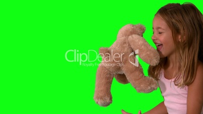 Cute little girl catching teddy bear on green screen and jumping