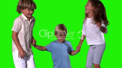 Siblings holding hands and jumping on green screen