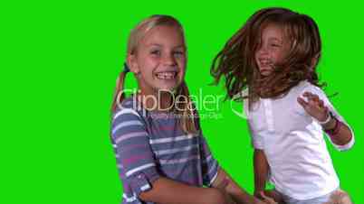 Sisters jumping on green screen with teddy