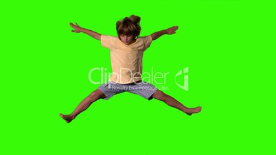 Little boy jumping with limbs outstretched on green screen