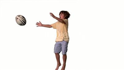 Little boy jumping and catching rugby ball on white background