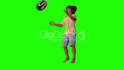 Little boy jumping and catching rugby ball on green screen