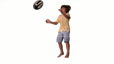 Little boy jumping up and catching rugby ball on white background
