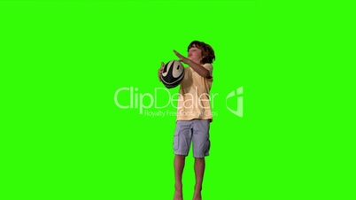 Little boy jumping up and catching rugby ball on green screen