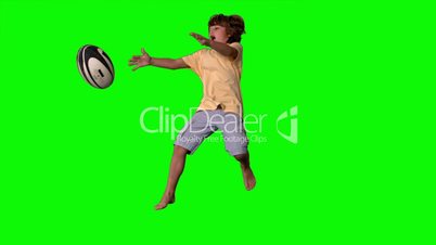 Little boy jumping up and catching a rugby ball on green screen