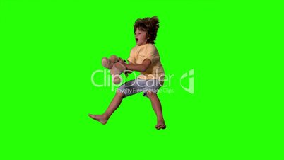 Young boy jumping up and catching teddy bear on green screen