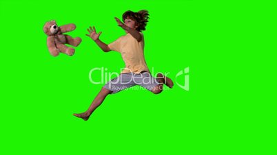 Little boy jumping up and catching teddy bear on green screen