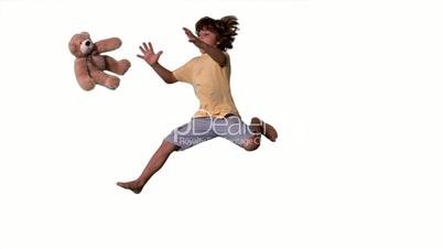 Little boy jumping up and catching teddy bear on white background