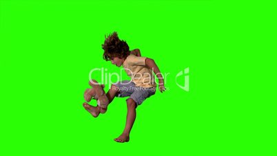 Little boy jumping up and kicking teddy bear on green screen