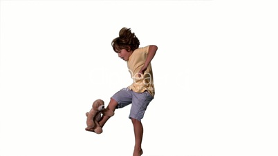 Little boy jumping up and kicking teddy bear on white background