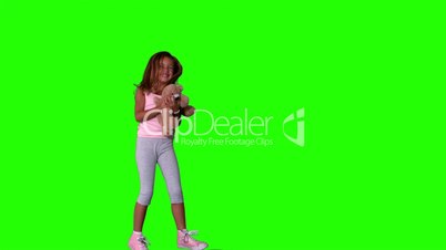 Little girl jumping and catching teddy on green screen