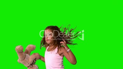 Little girl jumping up and turning with teddy on green screen