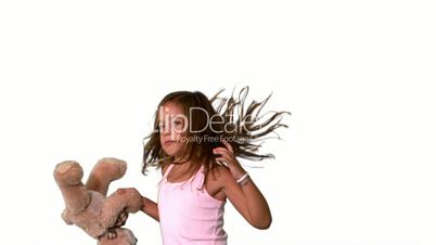 Little girl jumping up and turning with teddy on white background