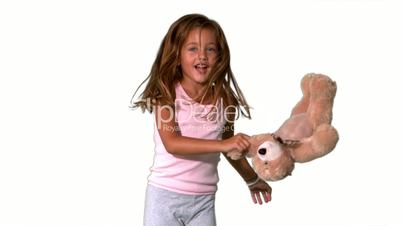 Little girl jumping up and down and turning with teddy on white background