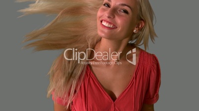 Attractive blonde tossing hair on grey background