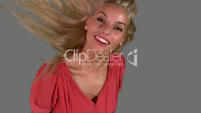 Attractive blonde tossing her hair on grey background