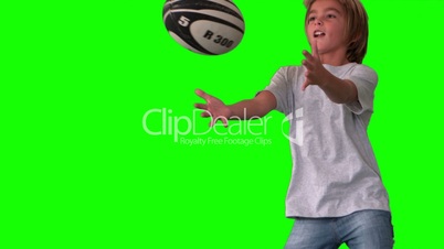 Boy jumping up to catch rugby ball on green screen close up