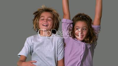 Brother and sister jumping up on grey background