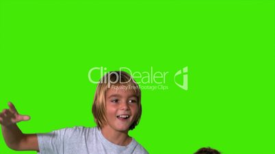 Brother and sister jumping up and crashing on green screen