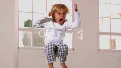 Boy in pajamas jumping and shouting in front of window