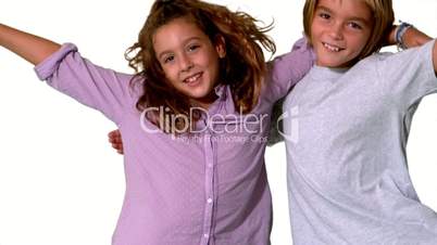 Brother and sister jumping into same shot and embracing on white background