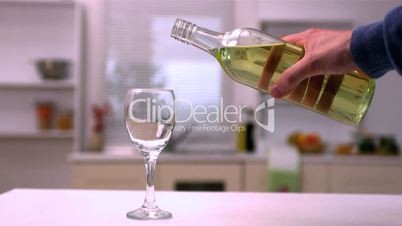 Hand pouring white wine into glass