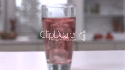 Four ice cubes spinning in a glass of juice