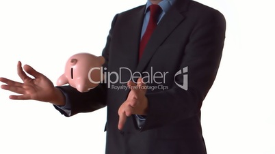 Man in a suit tossing a piggy bank