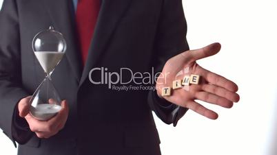Man holding an hourglass and dropping letter pieces spelling time