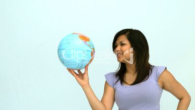 Smiling woman spinning globe on finger