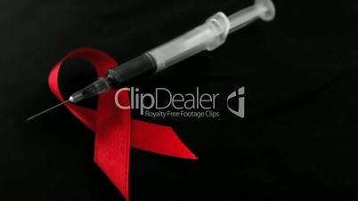 Syringe dropping down beside red ribbon