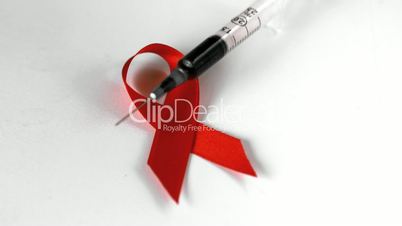 Syringe falling on red ribbon