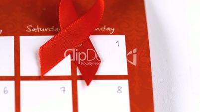 Red ribbon symbol for Aids falling on a calendar