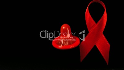 Condom dropping down in front of a red ribbon