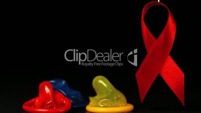 Coloured condoms dropping down beside red ribbon