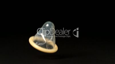 Condom falling over on black background