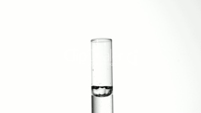 Drop of water falling into test tube of water close up