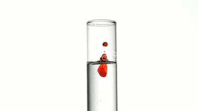 Drop of blood falling into test tube of water close up