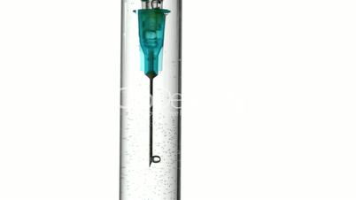 Syringe blowing bubbles in test tube of water close up