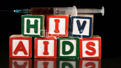 Syringe falling on wooden blocks spelling Aids and Hiv
