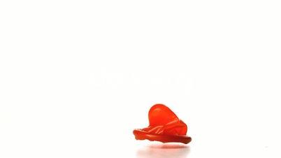 Red condom falling on white background