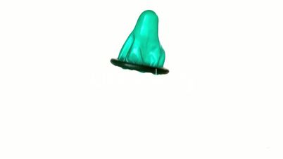 Green and yellow condoms falling on white background