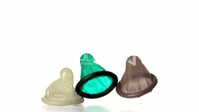 Three condoms falling on white background