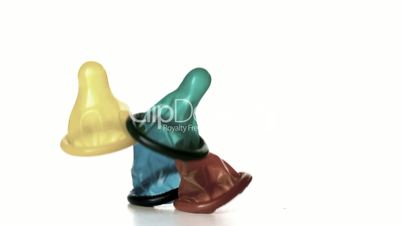 Four condoms falling on white background