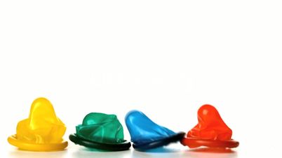 Four colourful condoms falling on white background