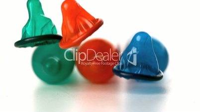 Colourful condoms falling in front of blown up condoms