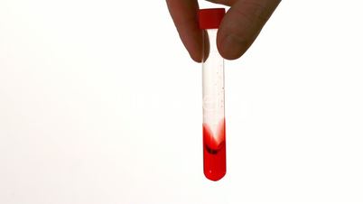 Hand swirling test tube of blood on white background