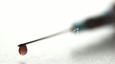 Drop of blood falling from syringe close up