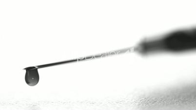 Drop of blood falling from syringe close up in black and white