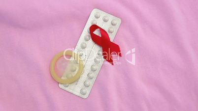 Contraceptive pill packet with condom with red ribbon